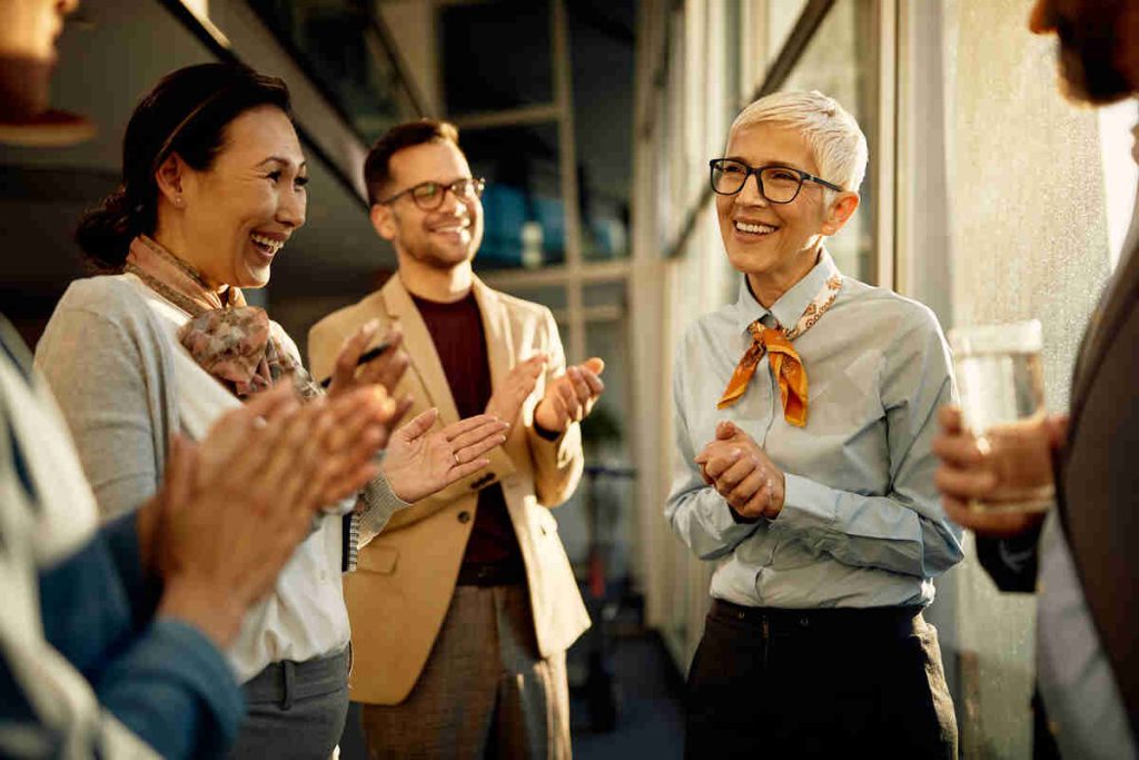 Happy employees celebrating the CEO of the business who is successful due to small business coaching.