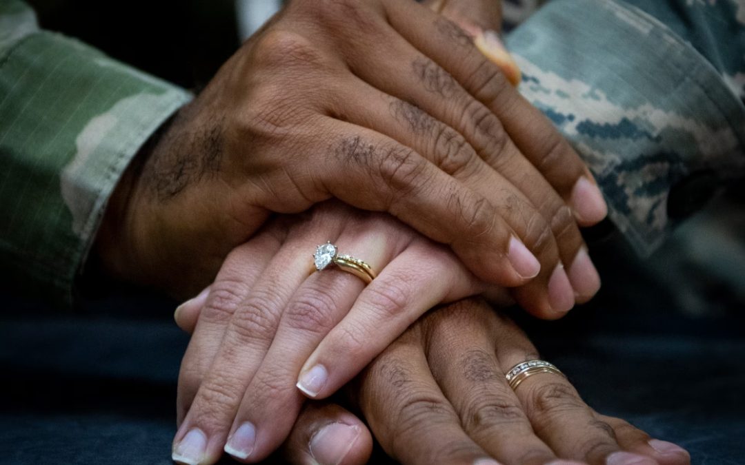 Hands stacked on top of each other showing wedding rings.